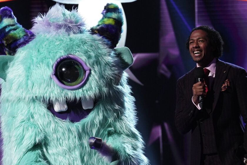 The Masked Singer -- Fox TV Series, THE MASKED SINGER: L-R: Monster and host Nick Cannon in the "Mask On Face Off" series premiere of THE MASKED SINGER airing Wednesday, Jan 2 (9:00-10:00 PM ET/PT) on FOX. © 2019 FOX Broadcasting. CR: Michael Becker / FOX. Nick Cannon, right, hosts "The Masked Singer" on Fox.
