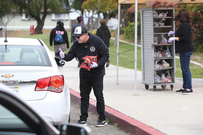 Danny Morris, principal at Huntington Beach High, distributes "grab and go" lunches to students and their families as they drive up to Ocean View High on Friday.