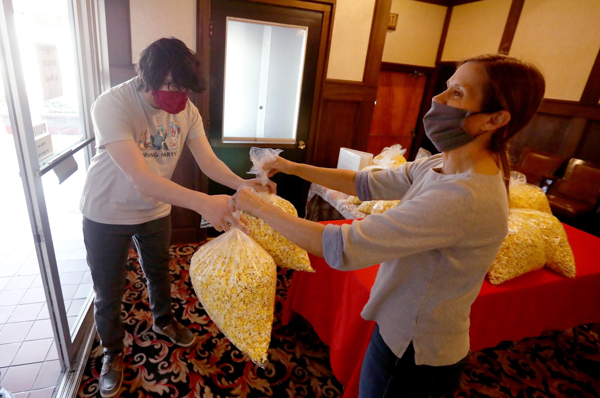 Bishop Theatre co-owner Holly Mullanix, right, serves up $10 bags of popcorn to a guest.