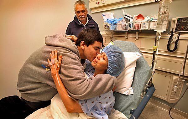 Before surgery, Gloria Lucio, 57, who has Alzheimer's, gets a hug and kiss from her son, Valentin, 18, as her husband, Don Jones, looks on. She is part of a clinical trial at UCLA Medical Center in which holes were drilled in her skull and either an experimental drug or placebo was injected into her brain.