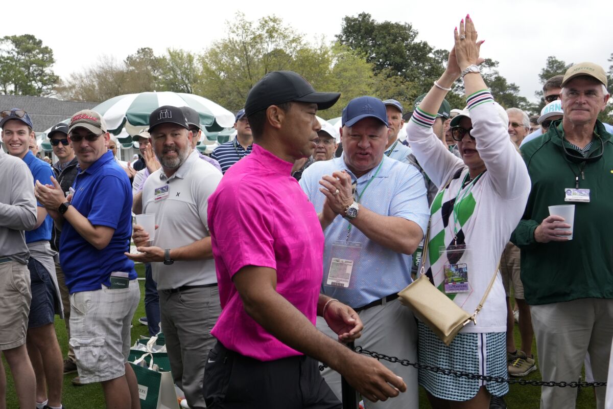 Spectators cheer as Tiger Woods heads to the first tee for the first round of the Masters golf tournament.
