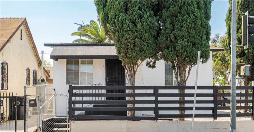 A white house with black trim and horizontal fencing in front.