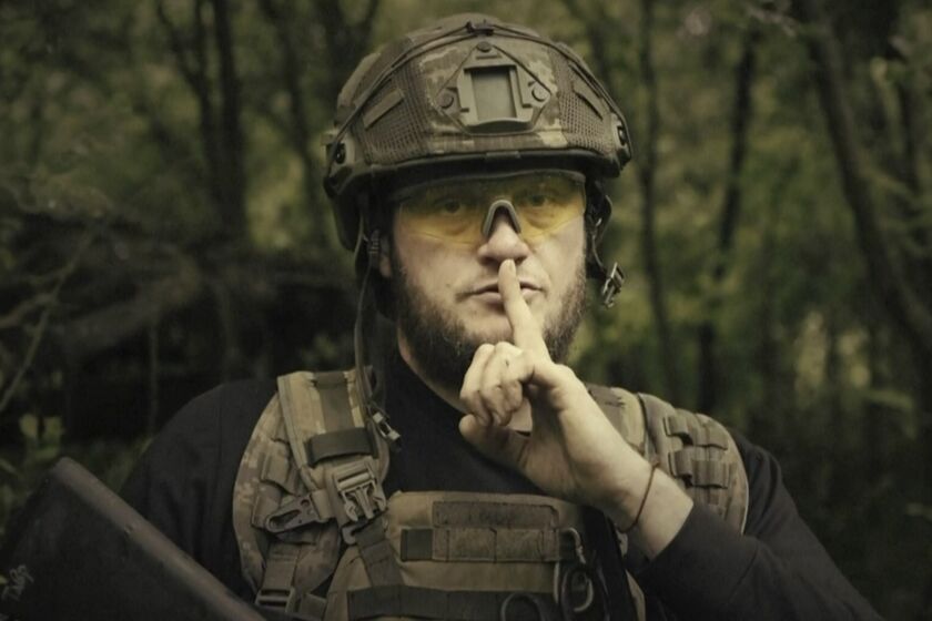 In this image made from video provided by Ukrainian Defense Ministry on Sunday, June 4, 2023, a Ukrainian soldier poses for the camera with his fingers to his lips, in an undisclosed location in Ukraine. A video released by the Ukrainian Defense Ministry on Sunday shows its military gesturing to silence suggesting that no formal announcement of a possible counter offensive against Russia will be made. The on-screen text of the video reads "Plans love silence. There will be no announcement of the start." (Ukrainian Defense Ministry via AP)