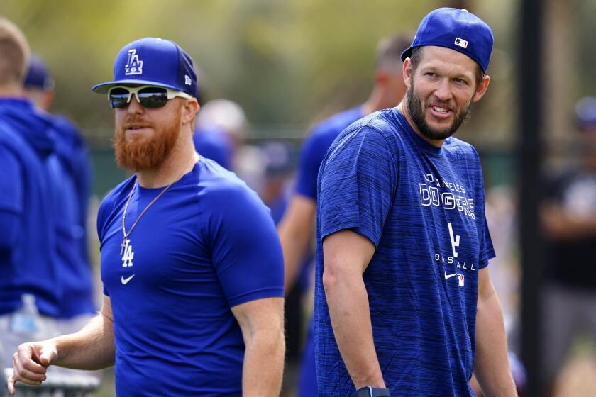 Los Angeles Dodgers' Justin Turner, left, wait to catch a ball as Clayton Kershaw walks behind him