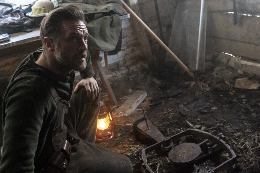 Devon Sawa examines a fur trap in the movie "Hunter Hunter."