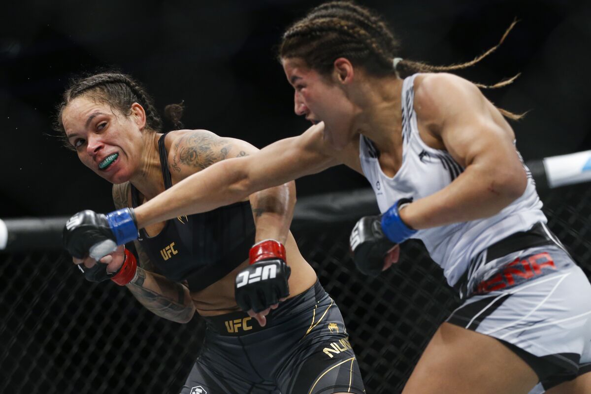 Julianna Pena, right, throws a right to Amanda Nunes during a women's bantamweight mixed martial arts title bout at UFC 269, Saturday, Dec. 11, 2021, in Las Vegas. (AP Photo/Chase Stevens)