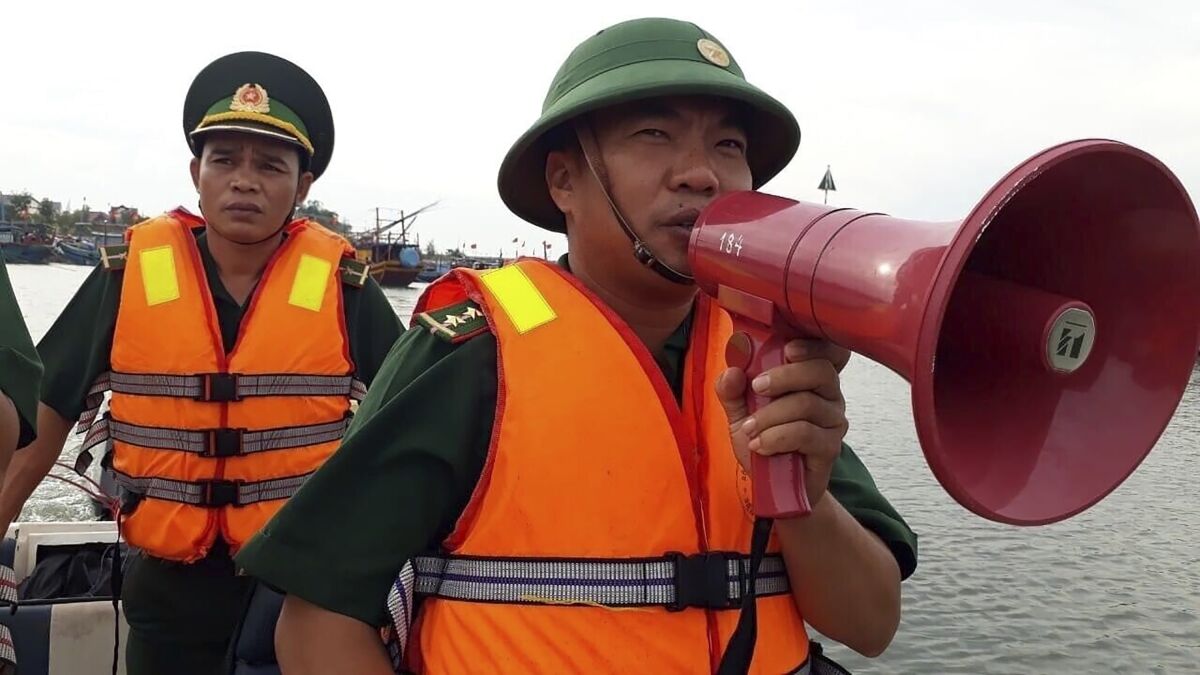 A coast guard officer speaks on a megaphone at a fishing boat shelter in Quang Binh province, Vietnam on Saturday, Nov. 14, 2020. Vietnam's authority has ordered some 460,000 people to be ready for evacuation ahead of Typhoon Vamco reaching the country's central coast. (Nguyen Duc Tho/VNA via AP)