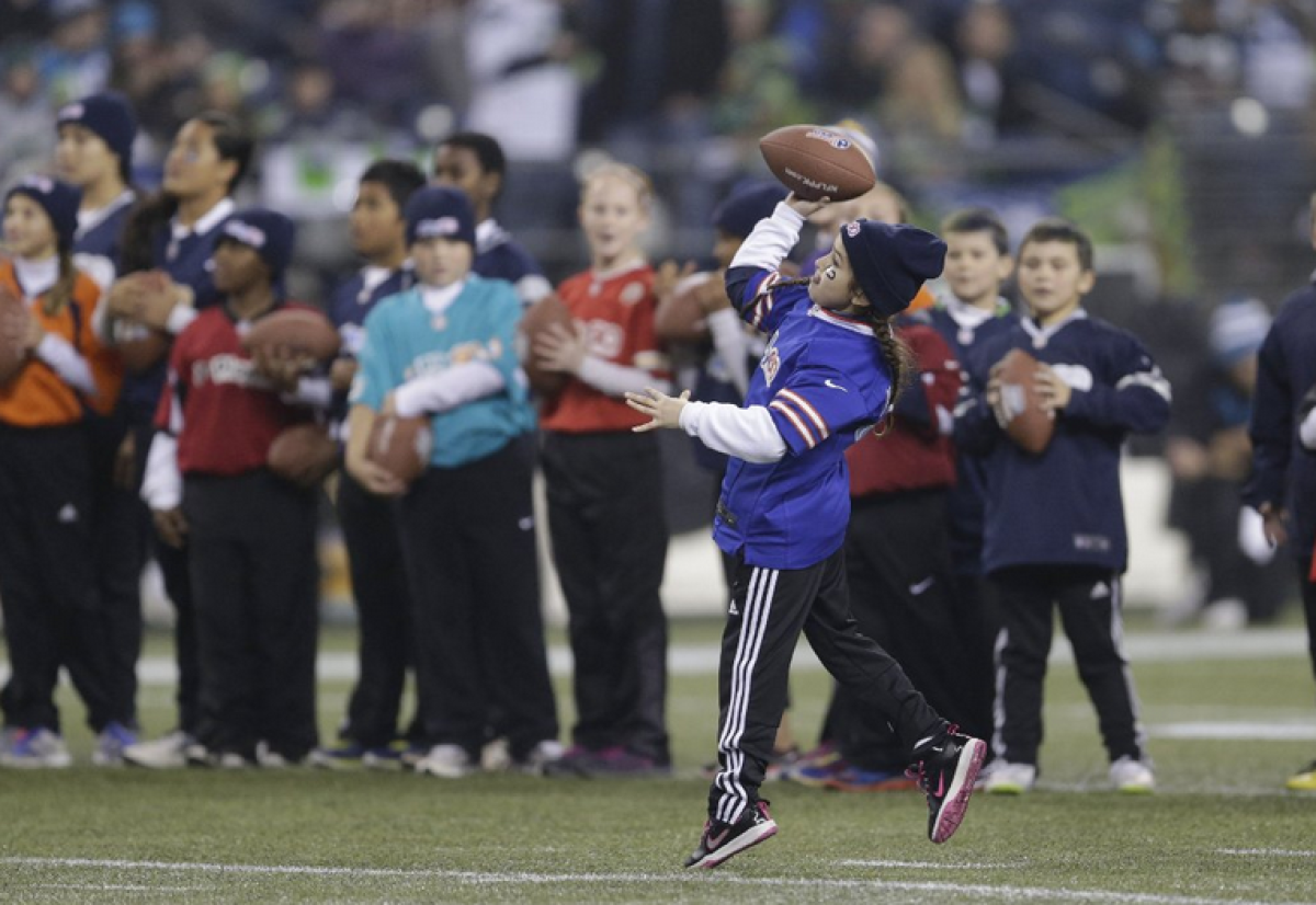 Kids participate in the punt, pass and kick competition during halftime of a playoff football game.