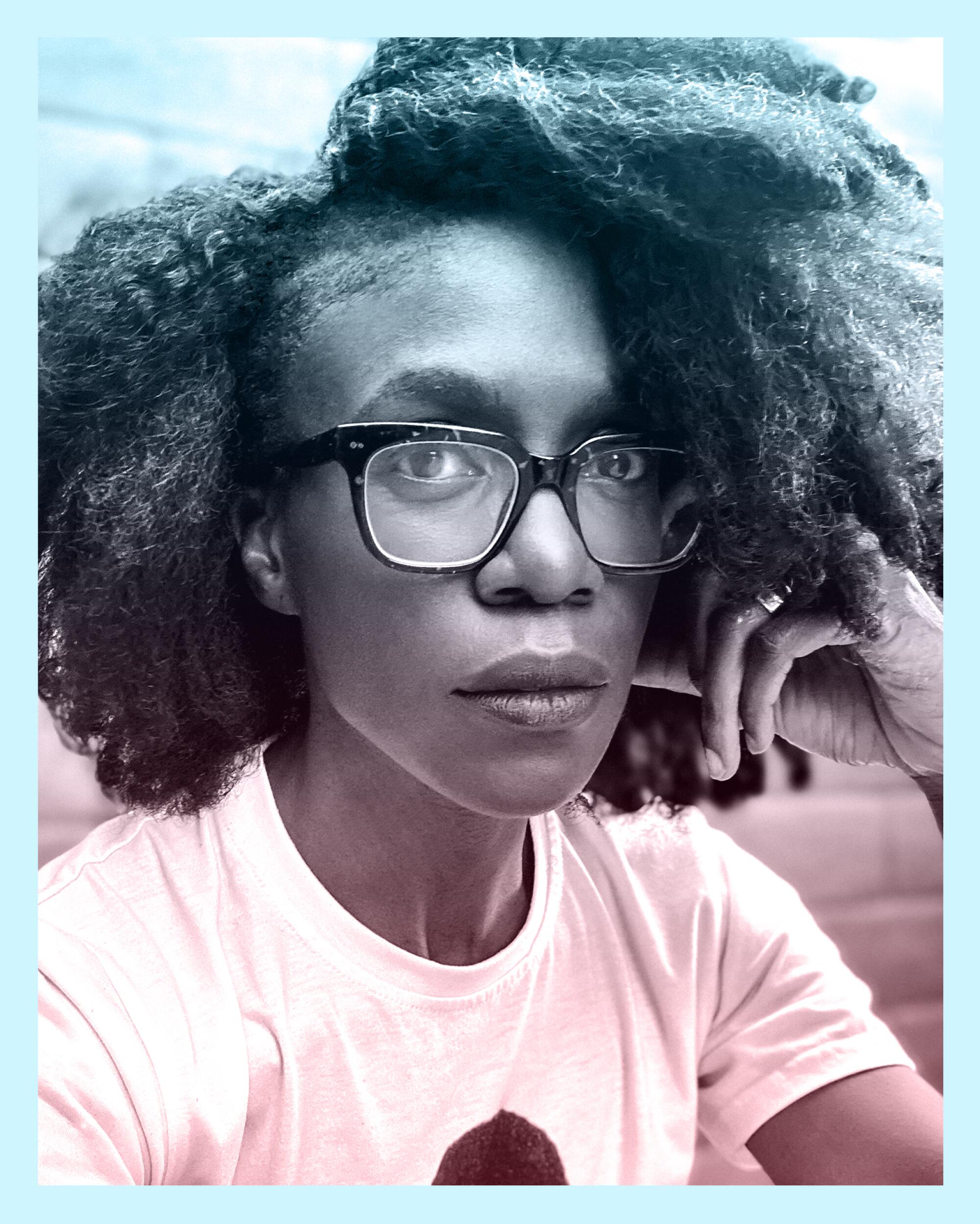 A Black woman with glasses looks intently at the camera.