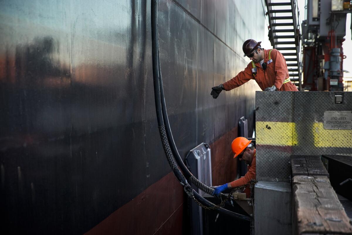 Crane mechanics Chris Guinn and Martin Viduka work to connect the Yang Ming Movement to shore power Wednesday in Wilmington.