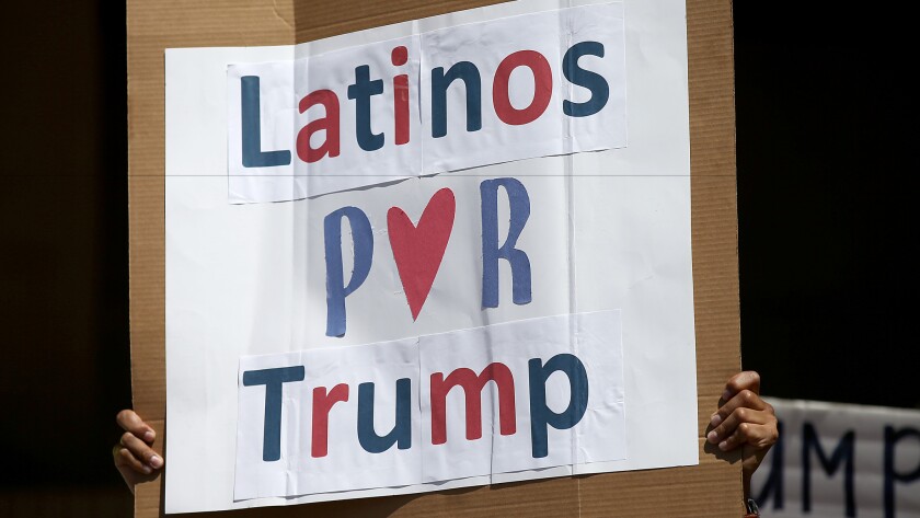 A man holds a sign reading "Latinos por Trump" at a rally for then-candidate Donald Trump outside Anaheim City Hall in 2016