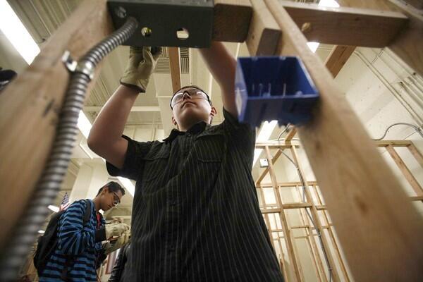 Andrew Araujo, 16, center, works on a junction box in Jesus Hernandez' Electrician class as Fernando Garcia, 15, left, helps at the Santee Construction Academy.