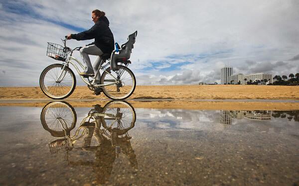 A cyclist rides along the bike path north of Santa Monica Pier in between rain showers Wednesday. See full story