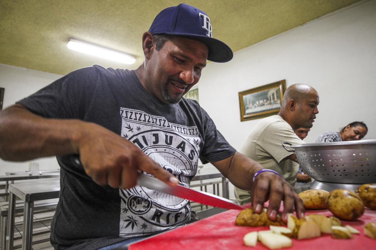 A man cuts potatoes at Casa del Migrante, a Tijuana shelter.