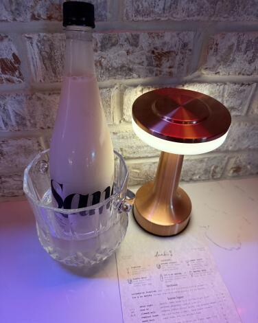 A bottle of makgeolli next to a small table lamp at Danbi.