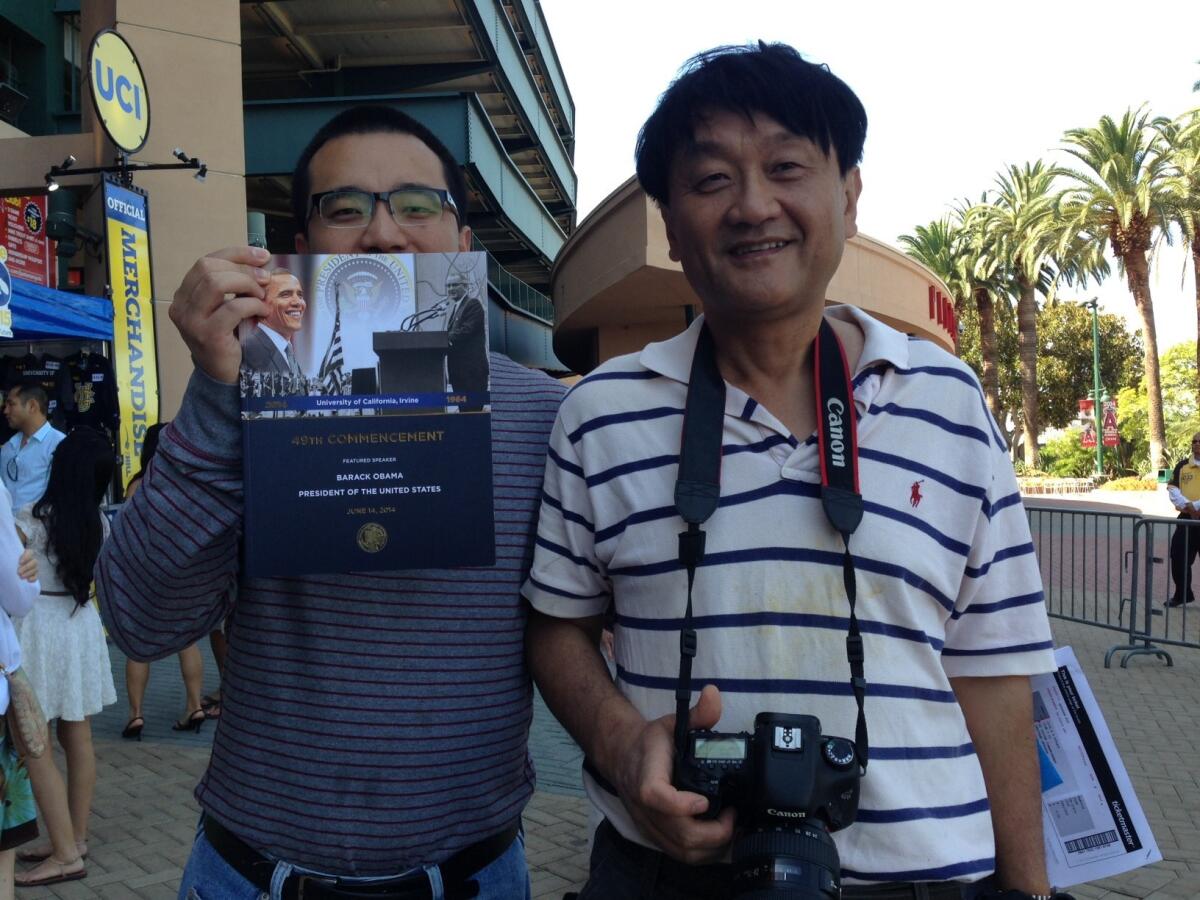 James Kou, right, with his son, Martin Kou, stand outside Angel Stadium of Anaheim, where they came to see Kou's other son, Abraham Kou, graduate. James Kou said he booked a flight from China immediately after learning that Obama would be speaking at UCI's commencement ceremony.