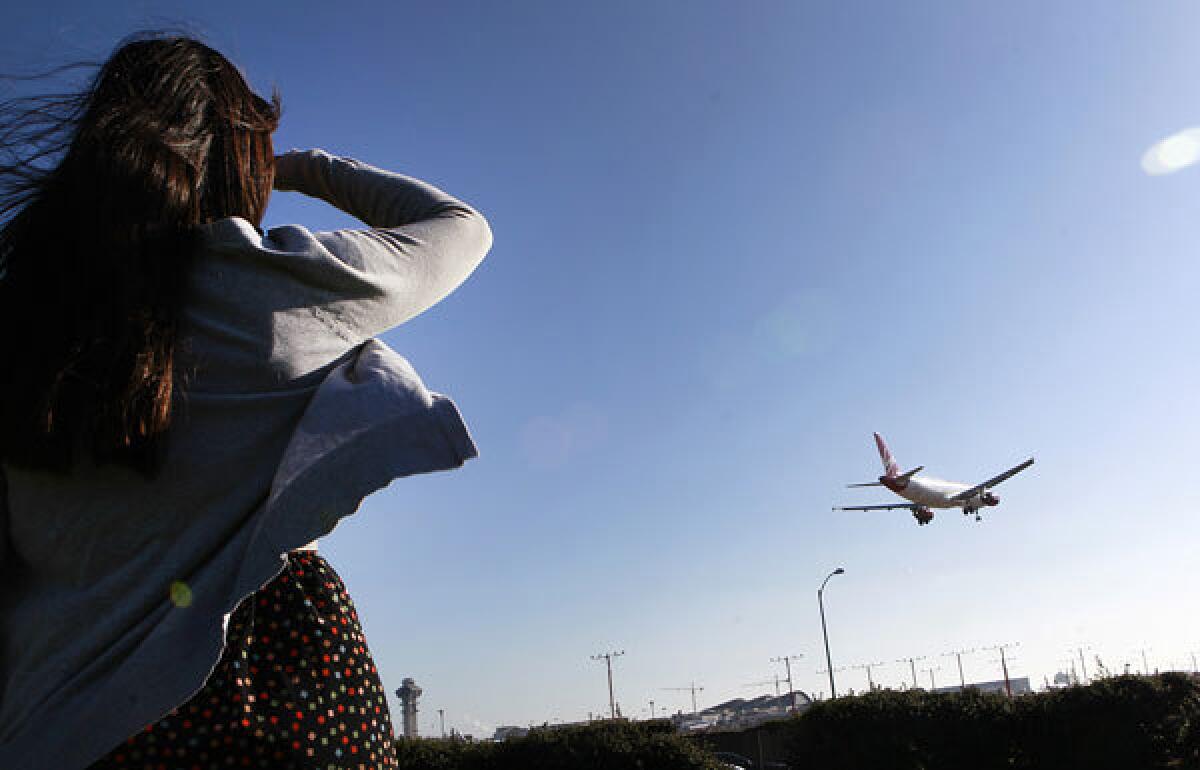 A woman watches a plane come in for a landing on the north runway at Los Angeles International Airport.