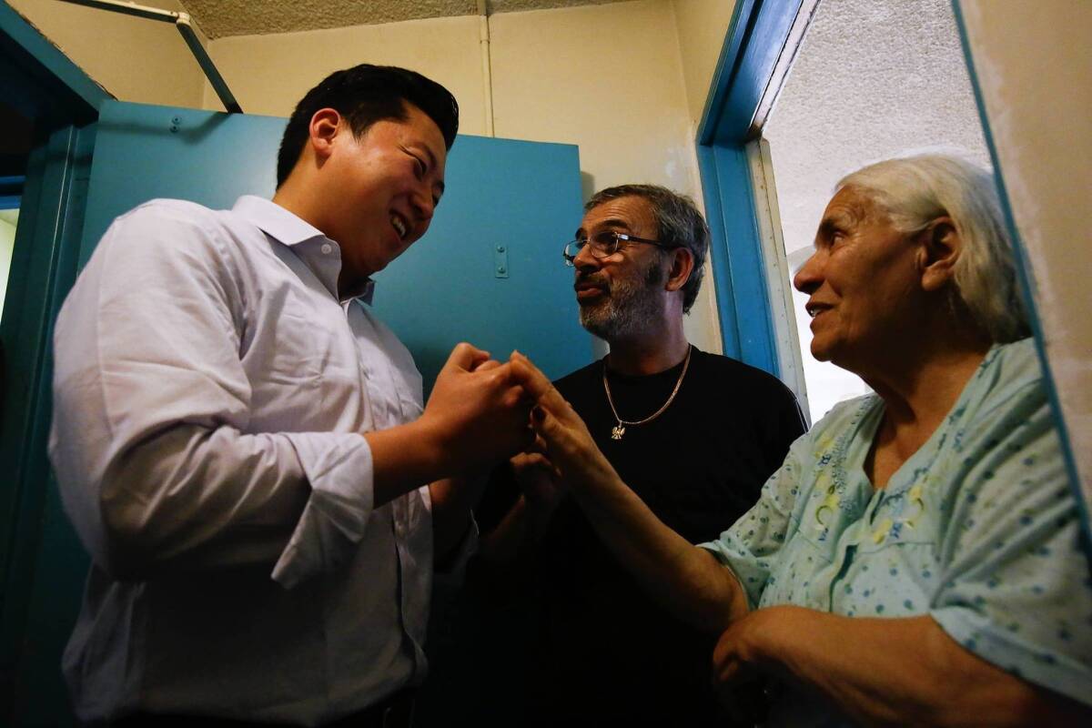 John Choi, left, a candidate for the L.A. City Council in District 13, talks with Yerdjanik Aloyan and his mother, Kima Toumasian, after a news conference held in response to threats allegedly made against his campaign workers as they canvassed the district.