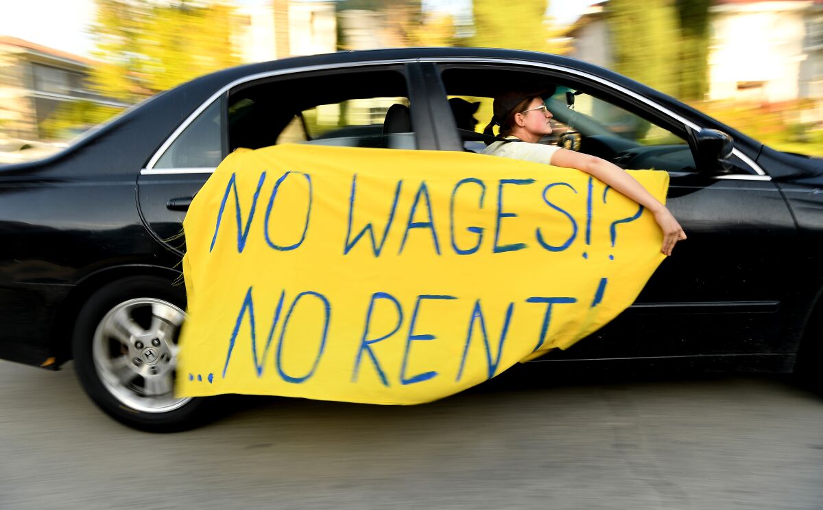 A protester drives by with a sign saying "No wages, no rent."