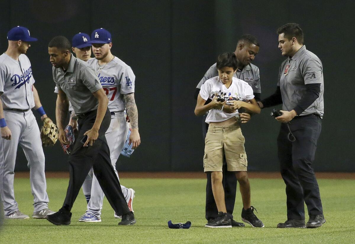 Chase Field security detained a spectator who ran onto the field before he reached Dodgers' outfielders, from left, Kyle Garlick, Enrique Hernandez and Alex Verdugo.
