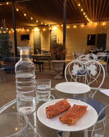 A plate with pan con tomate and the string-lighted patio at Le Champ.