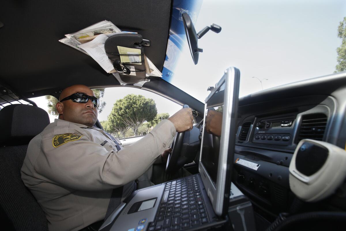 L.A. County sheriff's Deputy Michael Tadrous drives in a patrol car equipped with a dashboard computer last year.