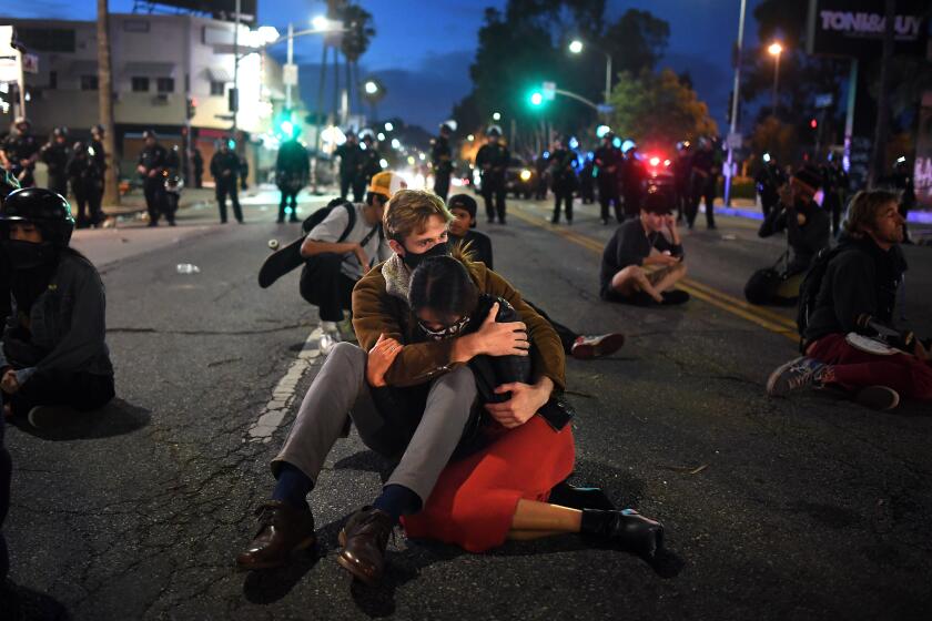 A couple consoles each other knowing they will be arrested along with protestors on Fairfax Ave. in Los Angeles Saturday.