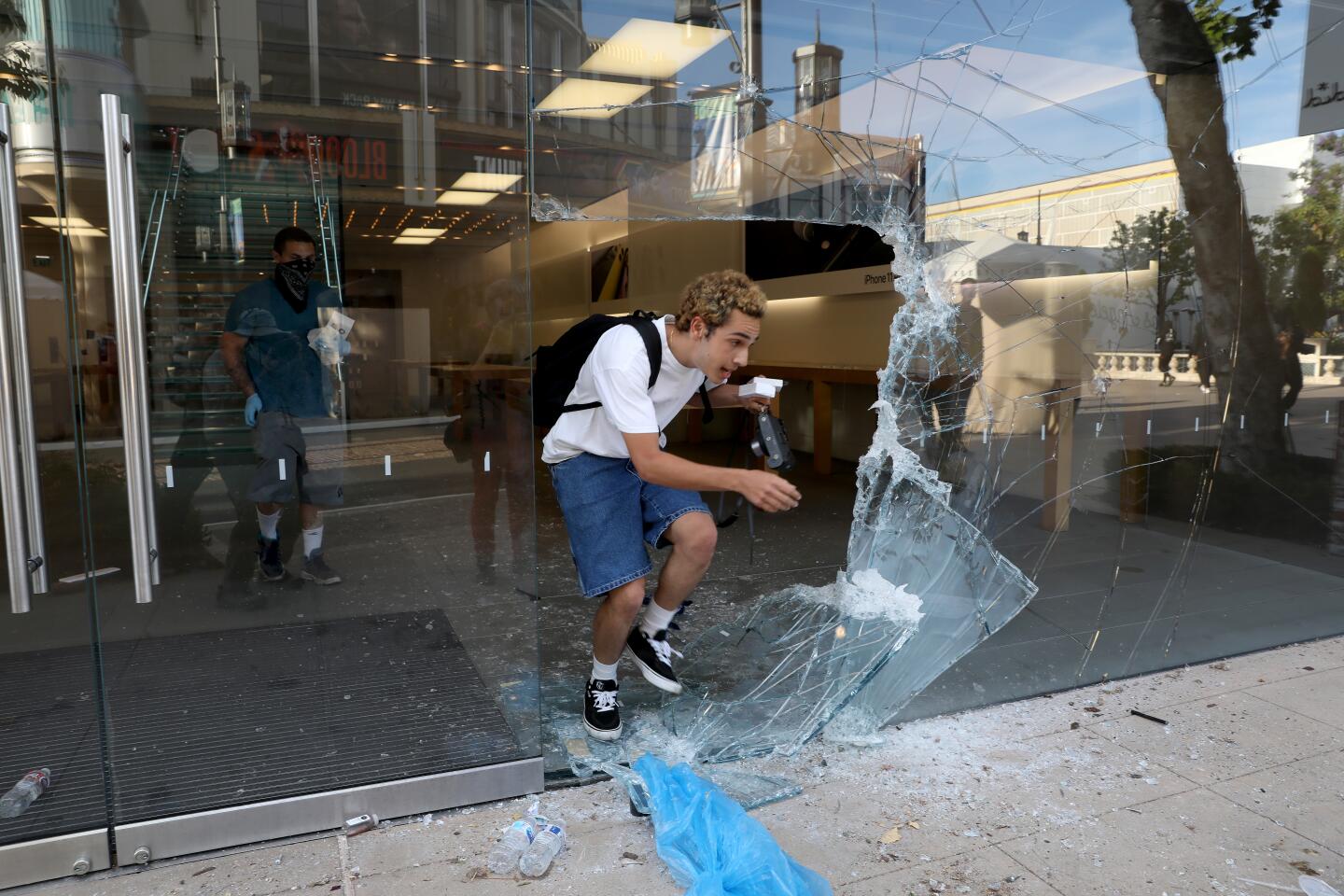 A man leaves the broken-into Apple Store with merchandise at the Grove in the Fairfax District in Los Angeles.