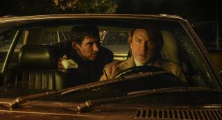 Two men have a tense discussion in a car at night.
