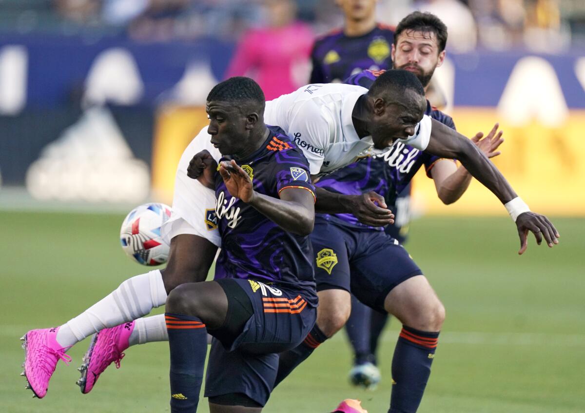 Galaxy defender Sega Coulibaly, center, collides with Seattle Sounders defender Abdoulaye Cissoko