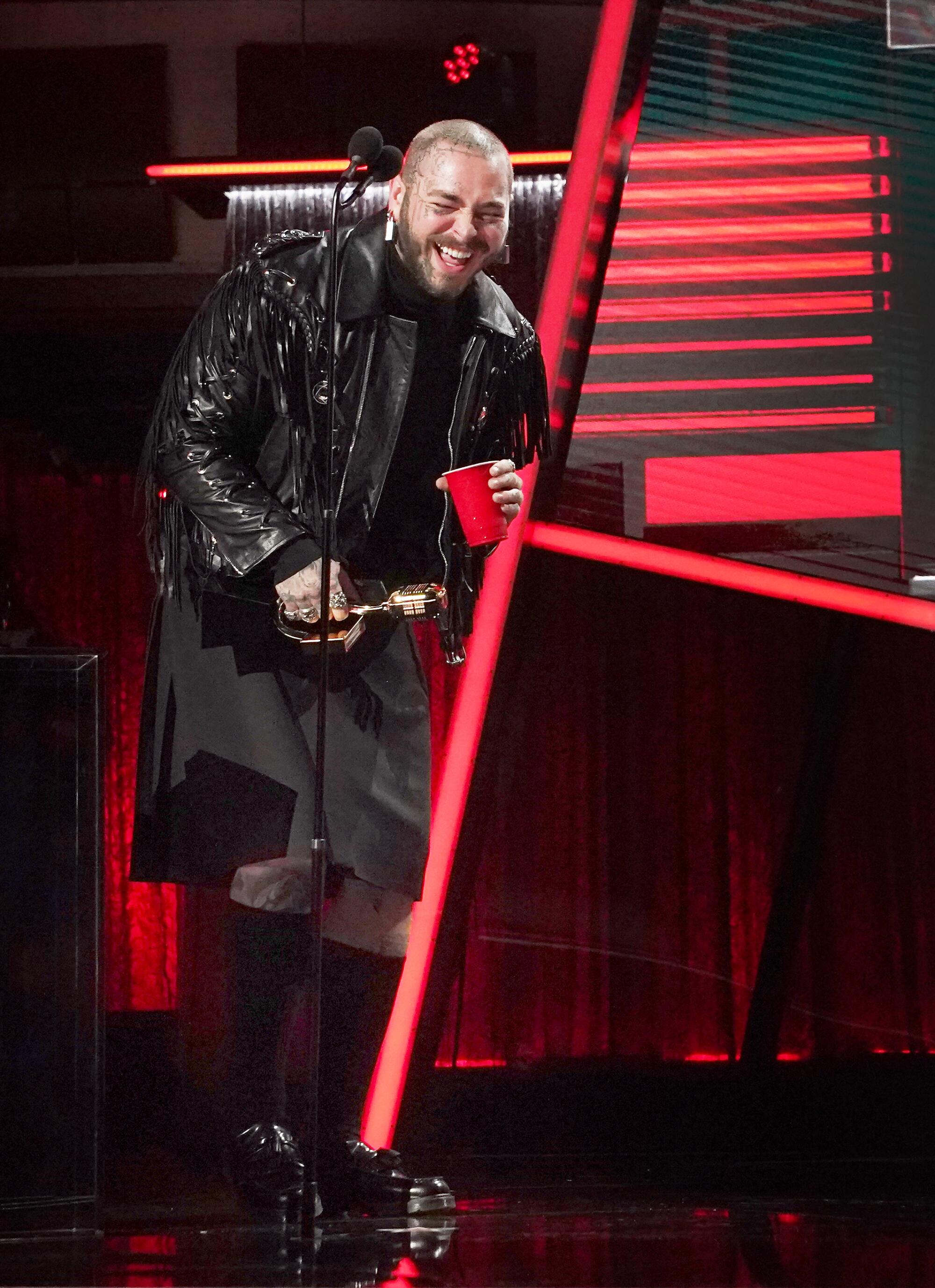 Post Malone laughs as he accepts an award.
