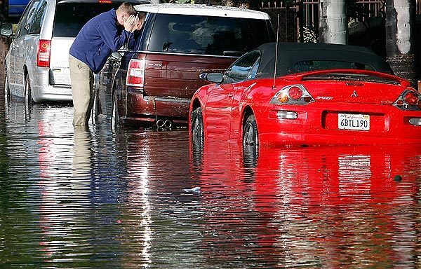 Eric Freed checks on his vehicle along a flooded stretch of Bennett Avenue in Long Beach.