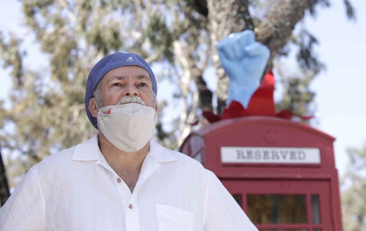 Laguna Beach artist Robert Holton stands next to his "Superhero Changing Station" on Forest Avenue, where it has been altered to thank first responders, medical staff and all essential workers during the coronavirus pandemic.