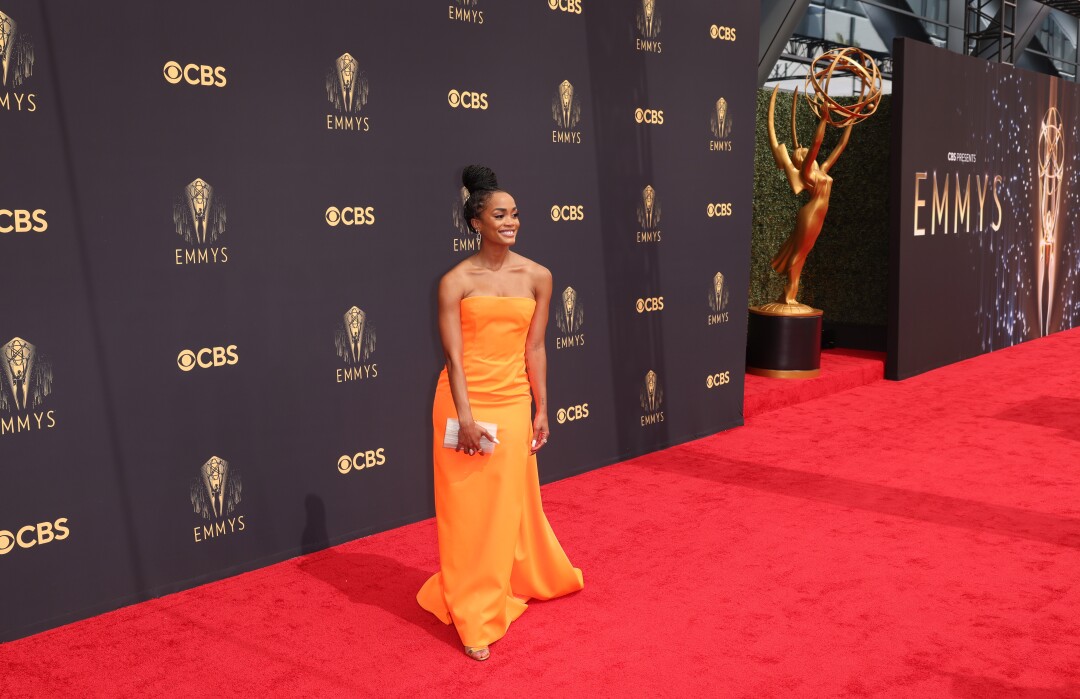 A woman holding a clutch in an orange dress