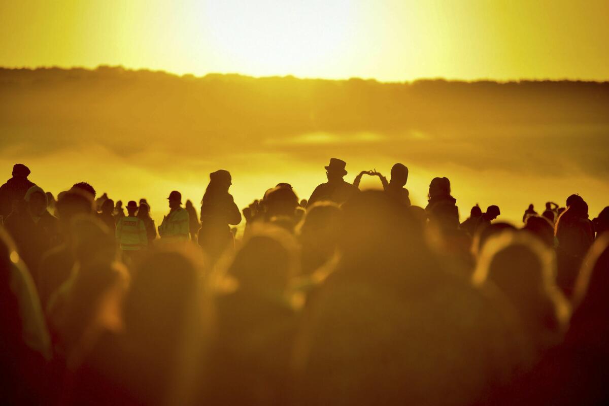 People turn to face the rising sun at Stonehenge.