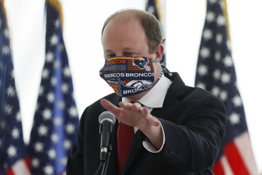 Colorado Governor Jared Polis wears a face mask as he answers a question during a news conference to update the state's efforts to stop the spread of the new coronavirus Wednesday, April 22, 2020, in Denver. (AP Photo/David Zalubowski)