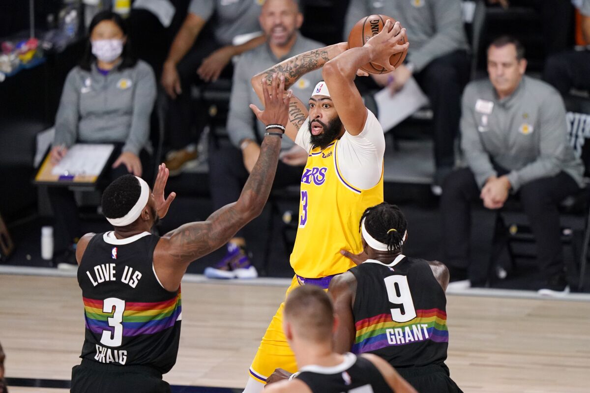 Lakers forward Anthony Davis looks to pass over Denver Nuggets forwards Torrey Craig and Jerami Grant.