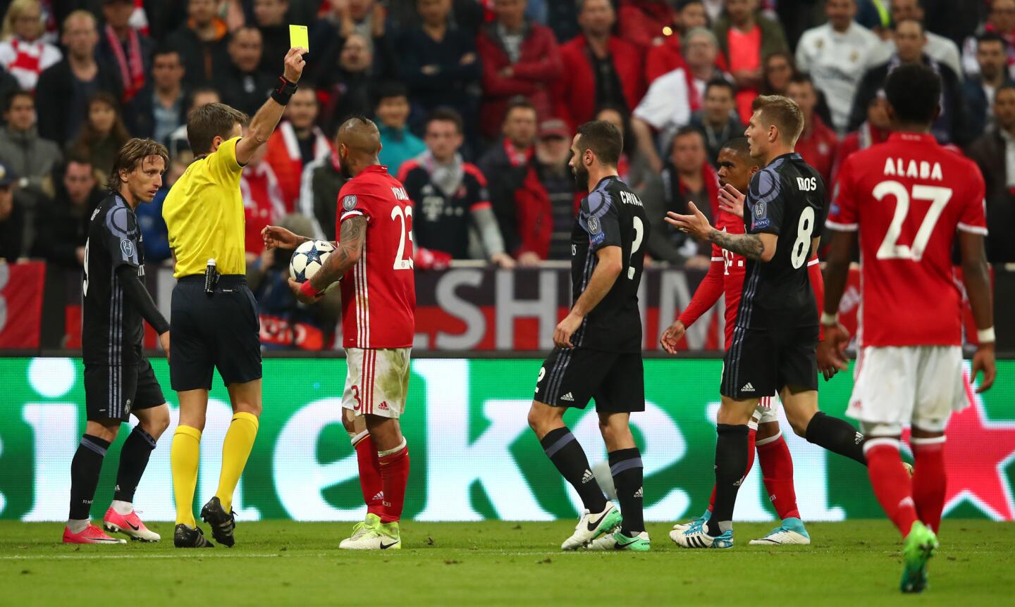 Bayern Munich's Arturo Vidal is shown a yellow card by referee Nicola Rizzoli