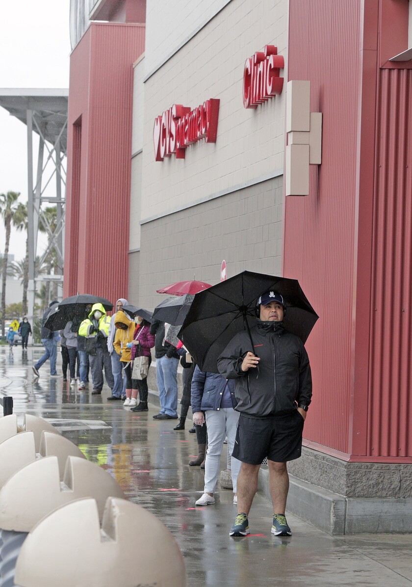 Shoppers wait in the rain at a physical distance from each other outside Target in the Empire Center in Burbank on Thursday. The Target Clinic, provided by Kaiser Permanente, is temporarily closed due to the coronavirus pandemic.