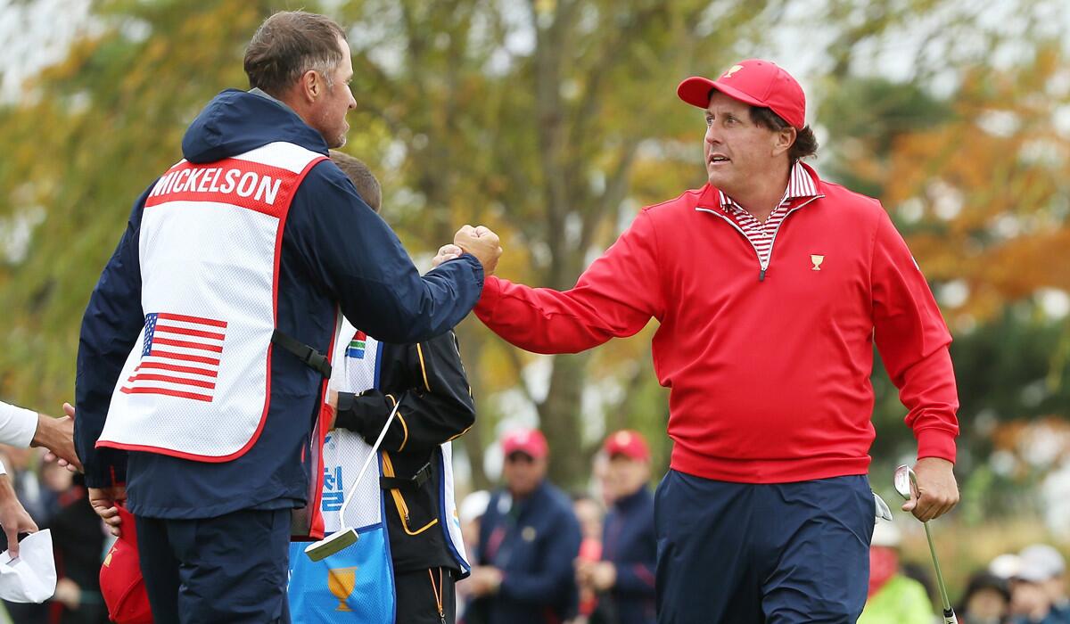 Phil Mickelson of the United States Team shakes hands with his caddie Jim Mackay after defeating Charl Schwartzel of South Africa and the International Team on Sunday.