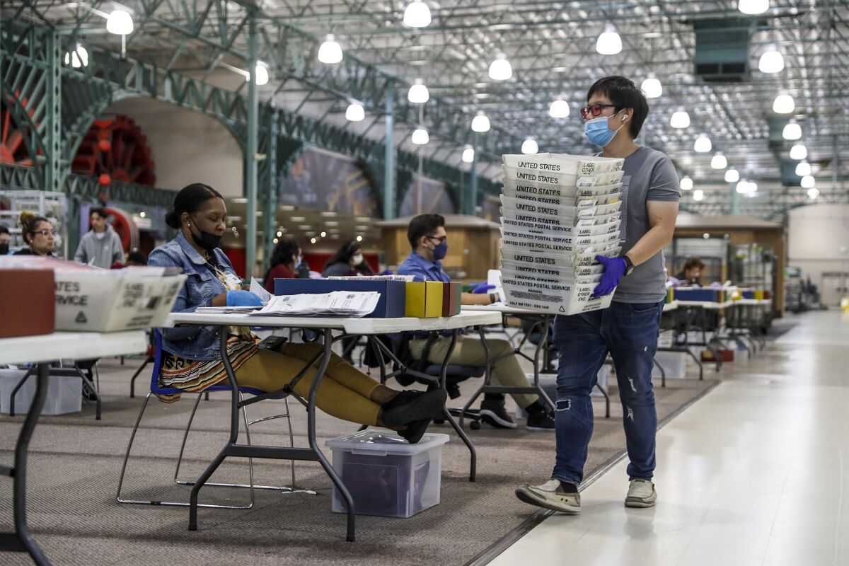 Workers sit at tables counting ballots.