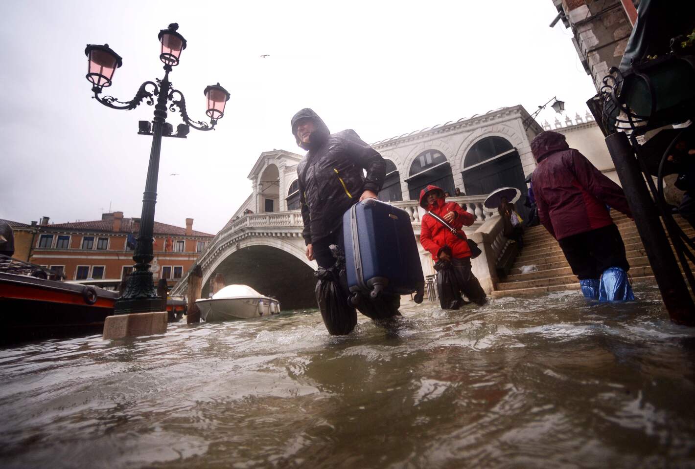 People carry their luggage in a flooded street near Rialto bridge in Venice, two days after the city suffered its highest tide in 50 years.