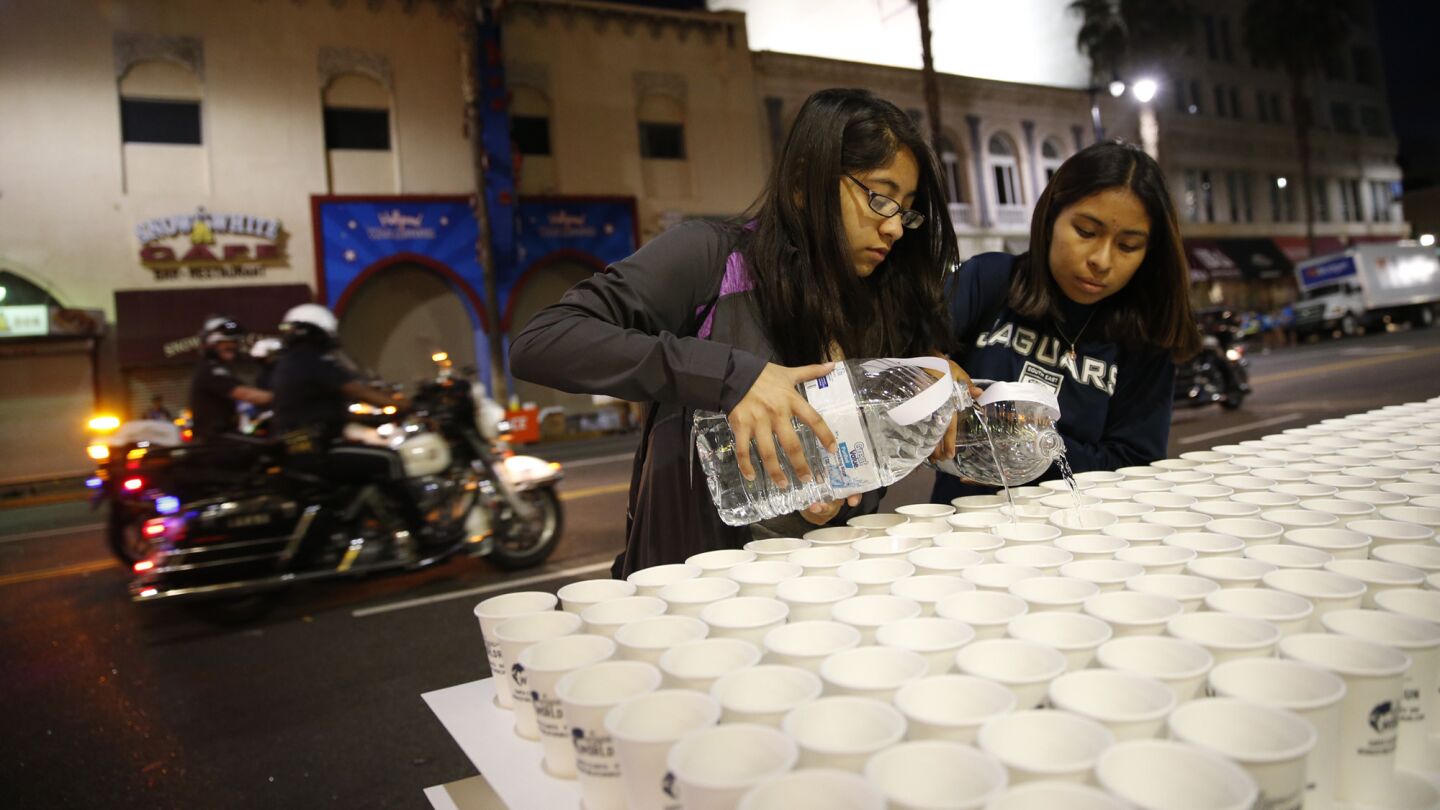 Lizeth Tamayl and Lizbeth Rojas pour water for runners on Hollywood Blvd. before the start of the 30th Los Angeles Marathon on Sunday in Hollywood.