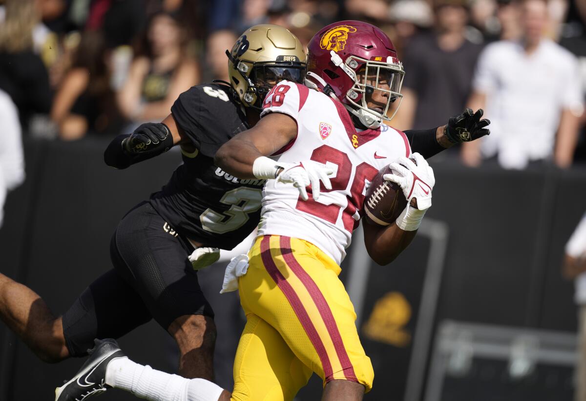 USC running back Keaontay Ingram, right, is dragged down by Colorado cornerback Christian Gonzalez.