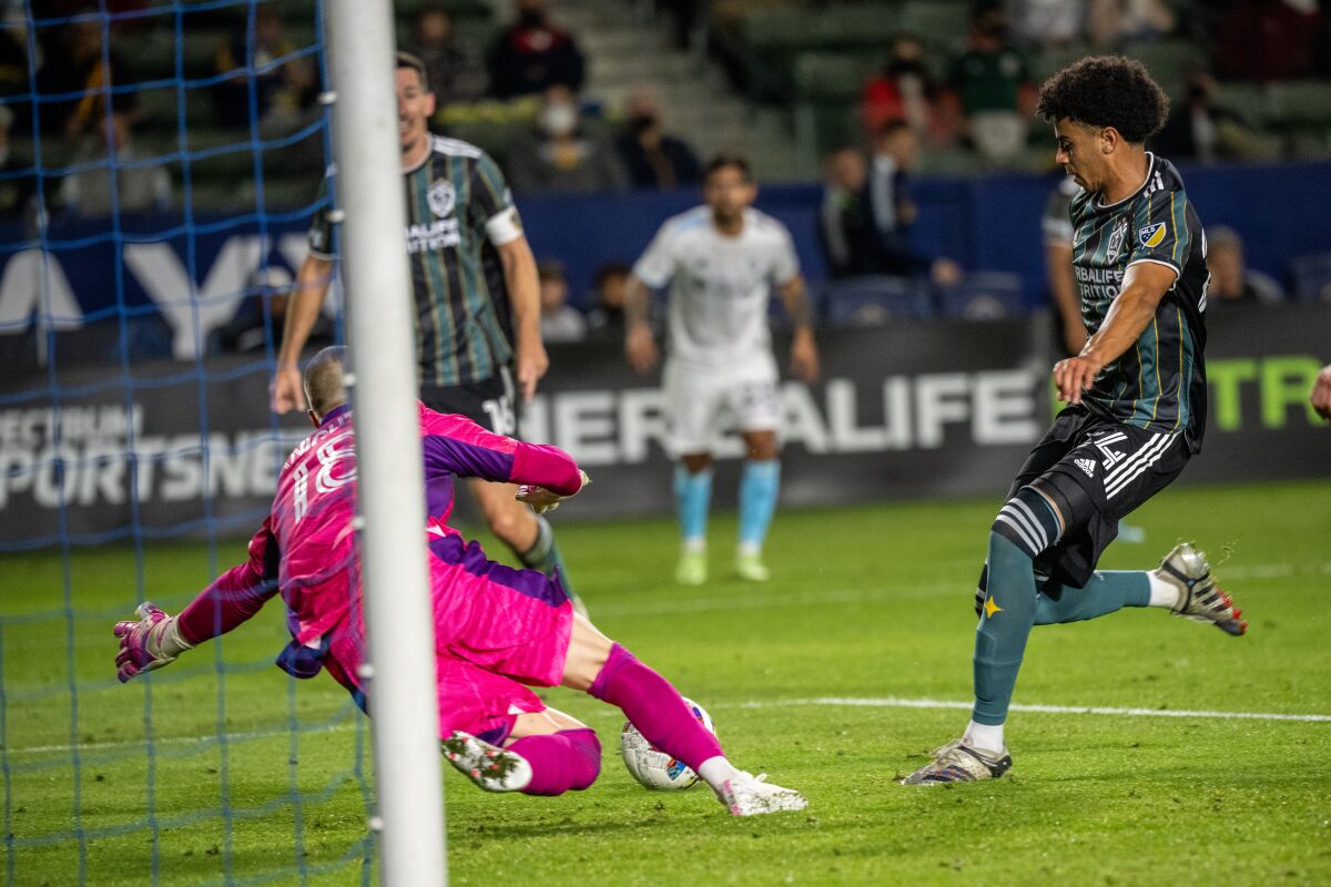 Galaxy's Jalen Neal has a shot on goal as New England Revolution's Brad Knighton makes a save during a match.