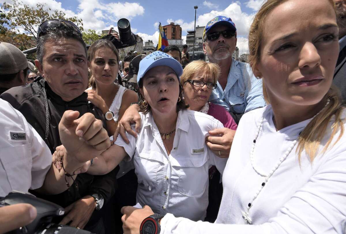Mitzy Ledezma, center, wife of Caracas Mayor Antonio Ledezma, and Lilian Tintori, right, wife of jailed opposition leader Leopoldo Lopez, are surrounded by supporters after meeting in Caracas on Friday.