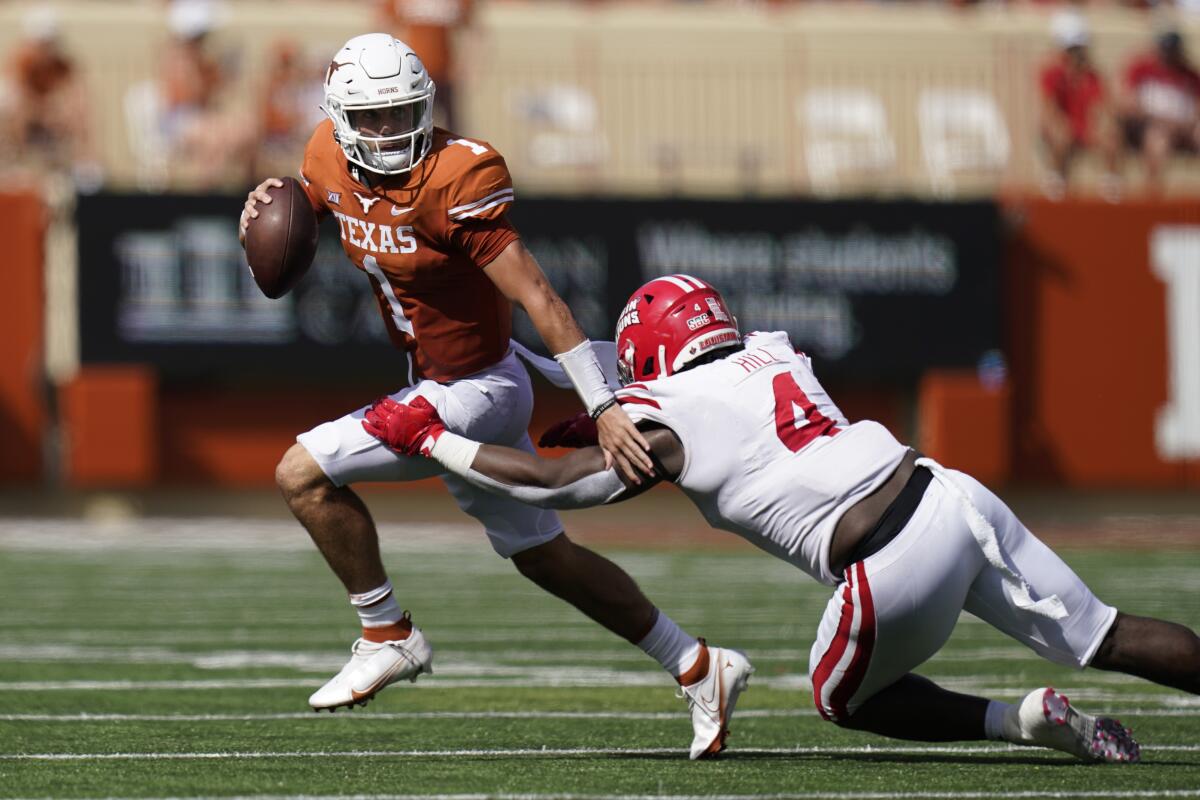 Texas quarterback Hudson Card (1) is pressured by Louisiana-Lafayette defensive lineman Zi'Yon Hill (4) during the first half of an NCAA college football game, Saturday, Sept. 4, 2021, in Austin, Texas. (AP Photo/Eric Gay)