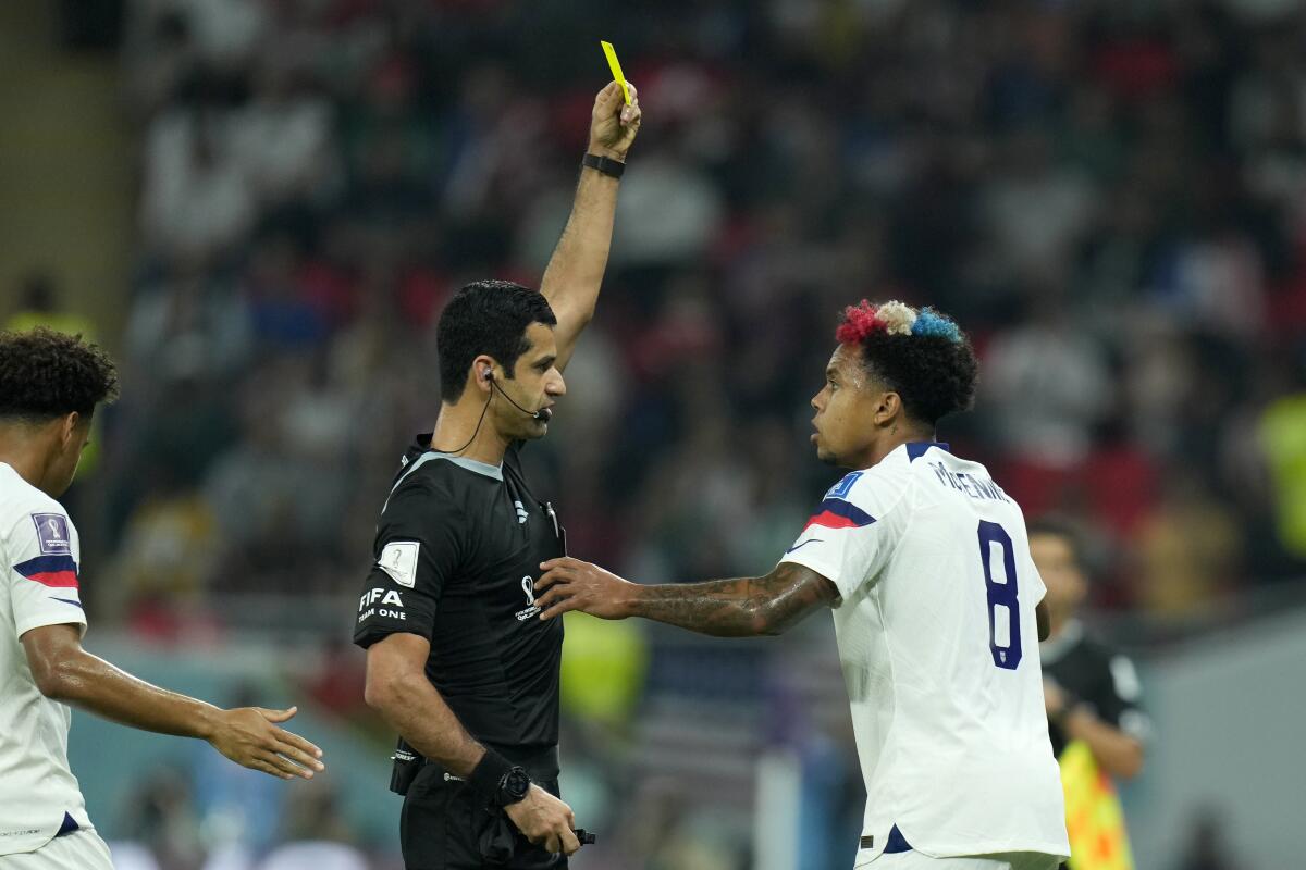 Referee Abdulrahman Al Jassim shows a yellow card to Weston McKennie of the U.S. for a foul on Wales' Neco Williams.
