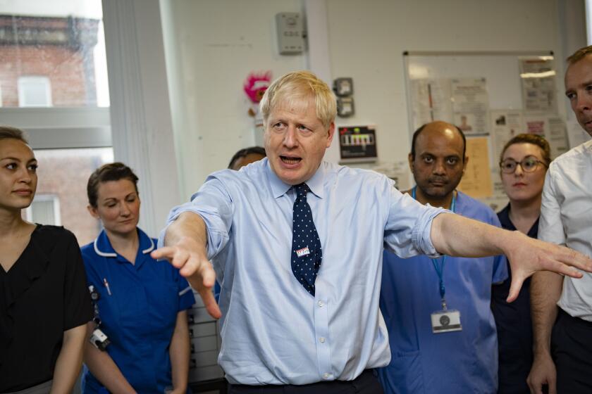 Britain's Prime Minister Boris Johnson looks on during a visit to North Manchester General Hospital before the Conservative Conference, in Manchester, England, Sunday, Sept. 29, 2019. British Prime Minister Boris Johnson has urged calm as tempers flare in the debate over Britain's departure from the European Union, even though tempers are flaring over what he said. A defiant Johnson told the BBC on Sunday that the "best thing for the country and for people's overall psychological health would be to get Brexit done." (Andy Stenning/Pool Photo via AP)