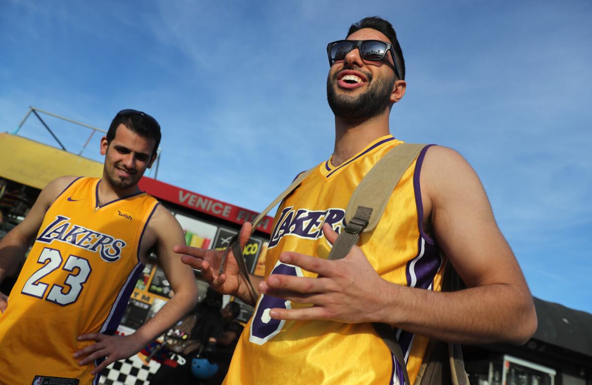 Friends Artin Azimi, 26, left, and Ramin Molaie, 26, both of San Jose, talk about Kobe Bryant on Friday on the boardwalk in Venice Beach.